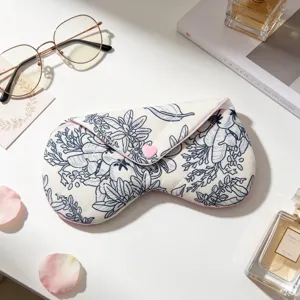 Detalle de una funda de tela para gafas con flores y un botón de corazón rosa en mesa