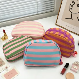 Detailed view of colorful striped canvas shell-shaped cosmetic bags with lifestyle props.