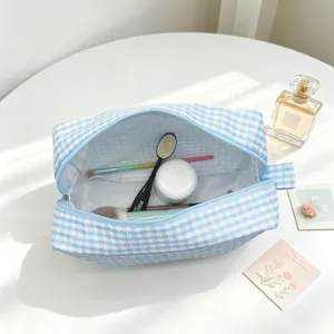 Detailed view of large blue gingham seersucker makeup bag with cosmetics inside