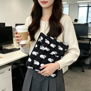 Detalle de funda acolchada para portátil con diseño de gato blanco en oficina