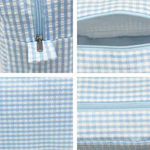 Close-up detail of blue gingham seersucker fabric and smooth metal zipper on cosmetic bag