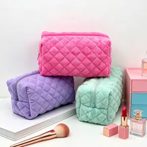 Detail van drie gewatteerde handdoek make-up tassen in snoepkleuren met accessoires.