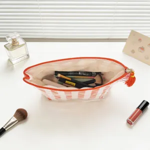 Detailansicht einer gestreiften PVC-Kosmetiktasche mit Pinseln und Make-up-Artikeln