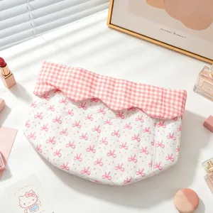 Close-up of pink bow patterned quilted fabric storage bag with gingham trim and scalloped edge