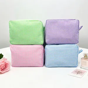 Set of four colorful gingham seersucker cosmetic bags for efficient travel organization.