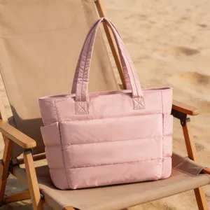 Grand sac fourre-tout matelassé rose sur une chaise de plage pour le voyage.