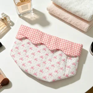 Detailed view of the pink bow pattern and gingham checkered trim on a quilted fabric storage basket