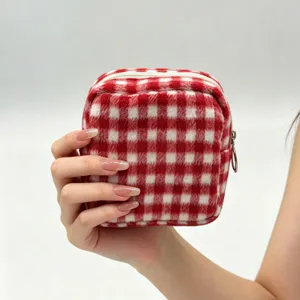 Close-up of a hand holding a red and white checkered fuzzy plush cosmetic storage bag