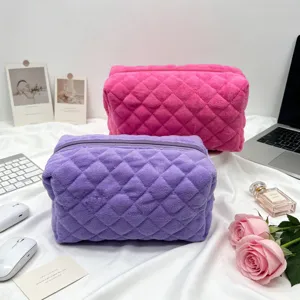 Detail van paarse en roze gewatteerde make-uptasjes van badstof op witte stoffen ondergrond.