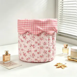 Pink floral quilted fabric storage basket with gingham trim on a vanity desk