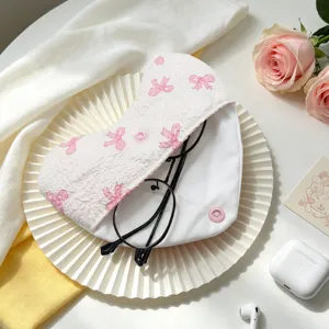 Primer plano de una funda de tela para gafas acolchada blanca con lindos lazos rosas