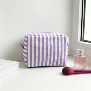 Purple striped seersucker cosmetic bag shown with perfume and makeup brush.
