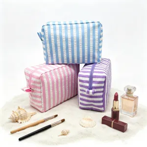 Macro detail of high-quality seersucker striped cosmetic bags in beach sand setting.