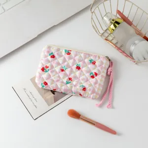Neceser acolchado con estampado floral en un escritorio con accesorios de belleza