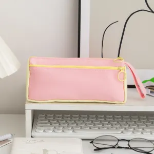 Detailed view of a cute pink and yellow canvas pencil case on a clean white desk setup