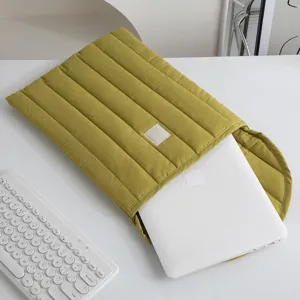 Detalle de cerca de la funda acolchada verde oliva para portátil con un portátil blanco