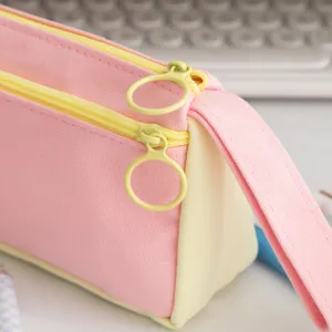 Close-up detail of pink and cream color-block pencil case with circular zipper pulls.