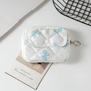 Vista detallada del mini bolso acolchado blanco con lazos azules y decoración