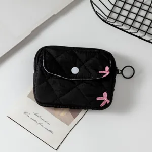 Primer plano de un mini estuche para auriculares acolchado negro con bordado de lazo rosa