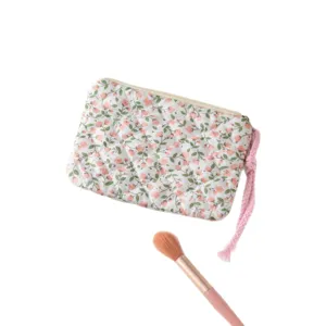 Neceser floral acolchado para maquillaje y accesorios sobre un fondo blanco impecable.