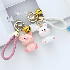 Close-up of cute pink pig and white rabbit resin keychains with knitted texture