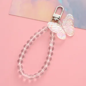 Makrodetail eines schillernden Schmetterlingsanhängers und transparenter Acrylperlen auf Pink