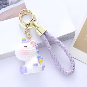 Detailed view of a cute cartoon resin unicorn keychain with purple braided strap
