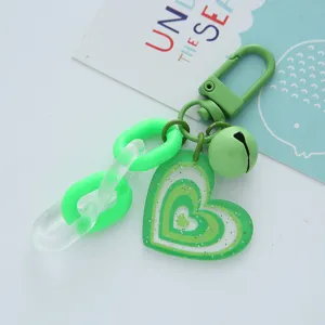 Close-up detail of a fresh green acrylic heart keychain with a matching bell and chain