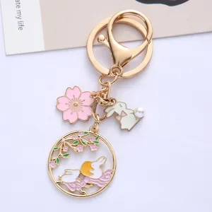 Close-up of cute rabbit and cherry blossom charms on a gold-tone alloy keychain.