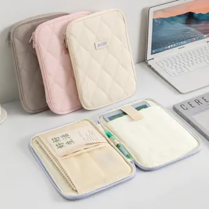 Detailed view of a quilted tablet sleeve with internal compartments for a pen and notebook.