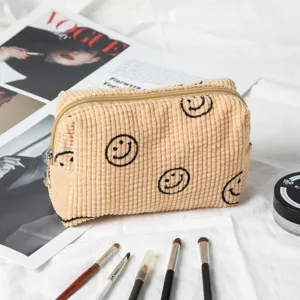 Detalle de neceser de pana con caritas sonrientes, brochas y revista Vogue