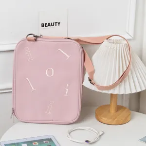 Minimalist pink iPad shoulder bag with embroidered letters on a lifestyle desk setup