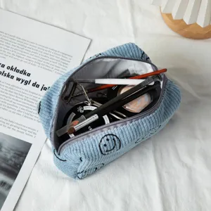 Primer plano de la bolsa de maquillaje de pana azul con cara sonriente y cosméticos