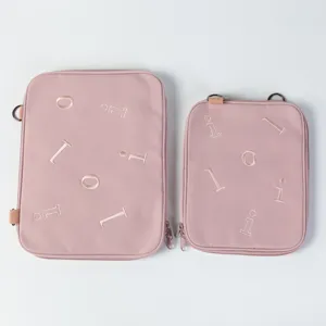 Close-up detail of two sizes of pink padded tablet and laptop sleeves with embroidery