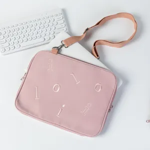 Pink laptop sleeve with adjustable shoulder strap shown on a desk with a white keyboard