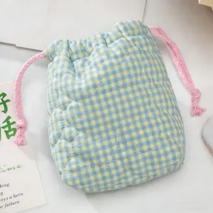 Détail du motif cœur matelassé sur la pochette Instax à carreaux bleus et jaunes