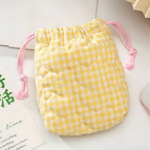 Gros plan sur la pochette matelassée jaune à carreaux avec cordon et motifs de cœurs.