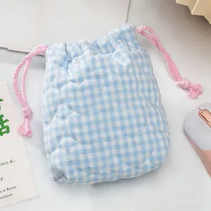 Gros plan sur le matelassage en cœur et le cordon rose d'un sac photo à carreaux bleus