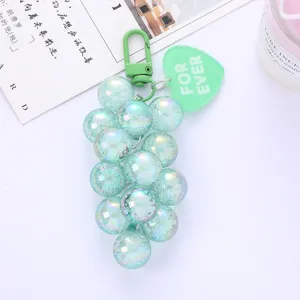 Close-up detail of a mint green iridescent grape bead keychain with a heart tag.