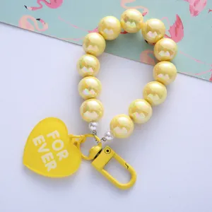Detailed view of yellow iridescent beaded keychain with heart pendant and FOR EVER text