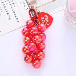 Close-up of a vibrant pink grape-shaped beaded keychain featuring a red heart tag