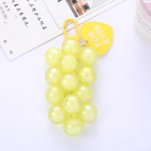 Close-up of a pearlescent yellow grape bunch keychain with a For Ever heart tag.