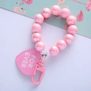 Close-up detail of pink pearlescent beads and heart-shaped tag on a stylish keychain