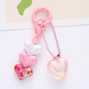 Detailed macro shot of colorful iridescent acrylic heart charms on a pink keychain accessory