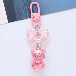 Iridescent acrylic teddy bear keychain with a cute pink bow and pearl accent detail
