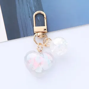 Close-up of a cute acrylic heart keychain with colorful clouds and iridescent bead.