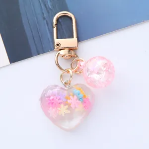 Close-up of a cute acrylic heart keychain with colorful snowflake charms for bag decor.
