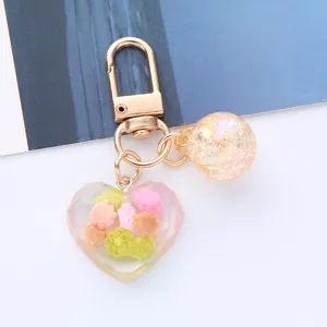 Close-up of a colorful heart acrylic keychain with iridescent bead and gold clasp