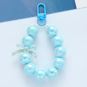 Llavero de cuentas azul irisado en colores caramelo con detalle de lazo de acrílico