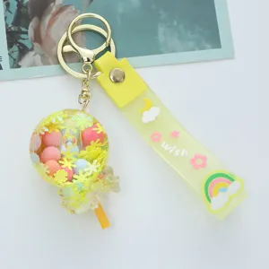 Detailed view of a yellow acrylic oil-filled lollipop keychain with a cute wish strap
